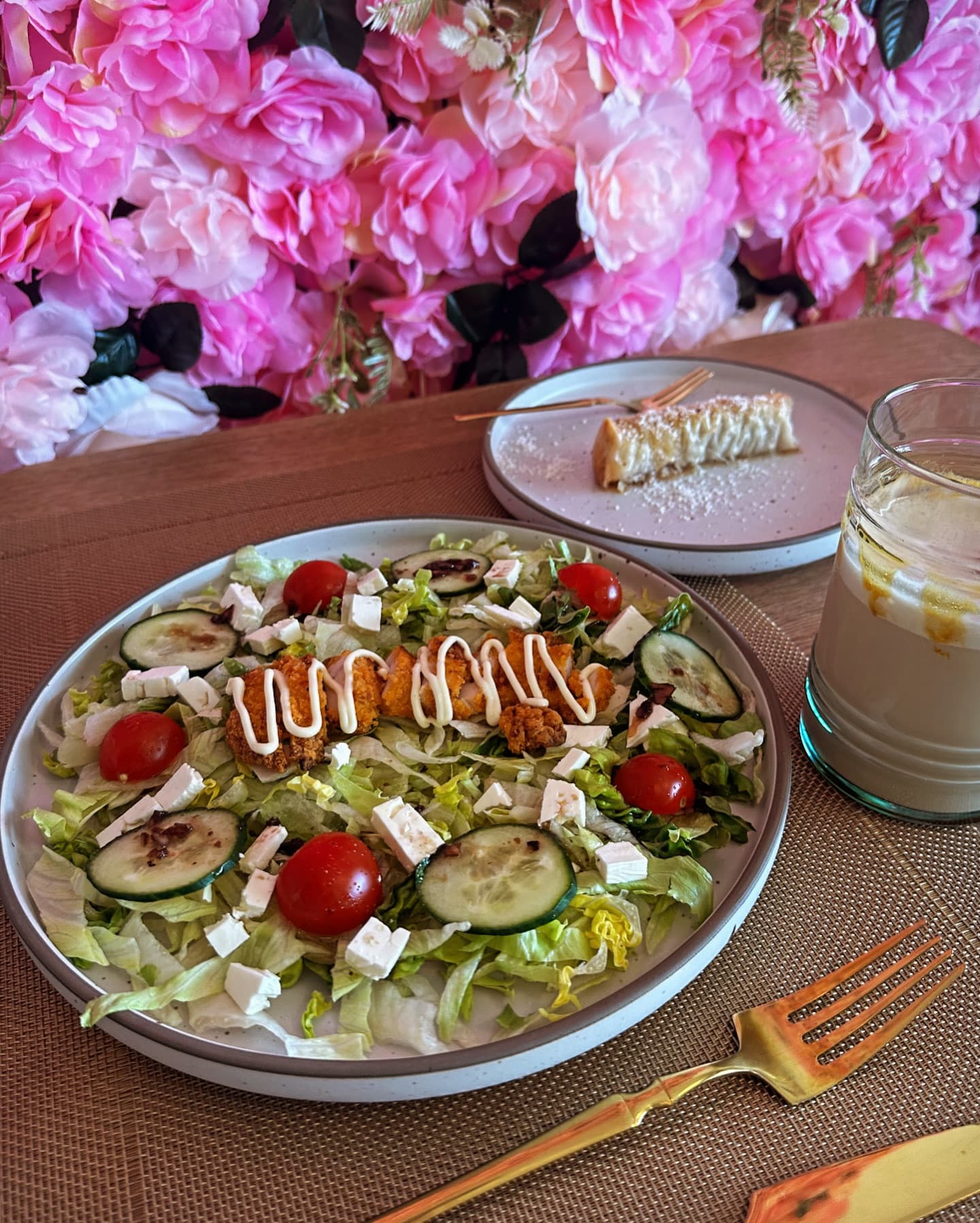 Salade fraîche, cheesecake et latte devant le mur de fleurs